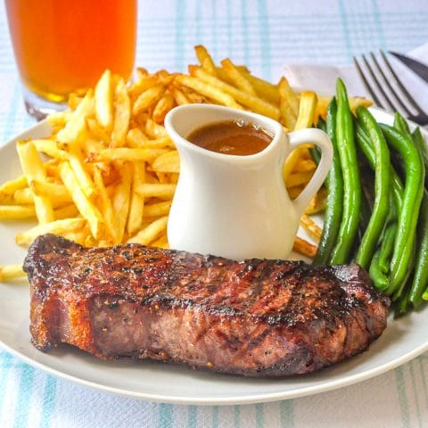 Steak Frites close up photo of single serving on white plate