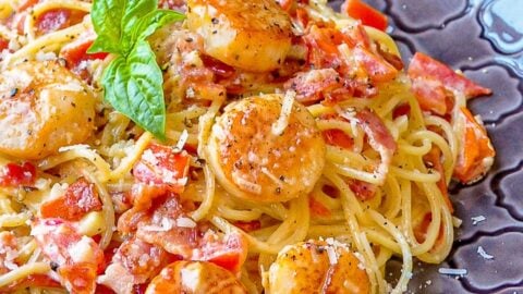 Creamy Garlic Scallop Spaghetti with Bacon close up photo of a single serving on a grey patterned plate