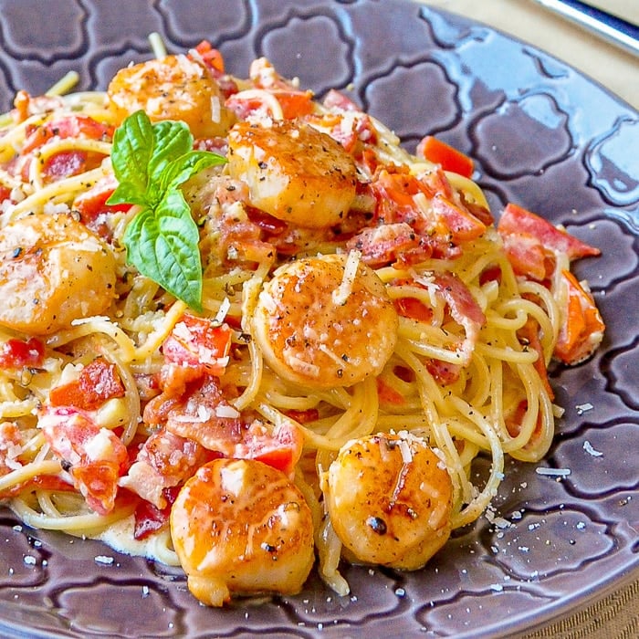 Creamy Garlic Scallop Spaghetti with Bacon close up photo of a single serving on a grey patterned plate