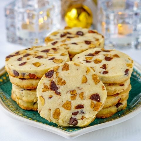 Chocolate Almond Shortbread Cookies close up image on green plate with christmnas decorations in background