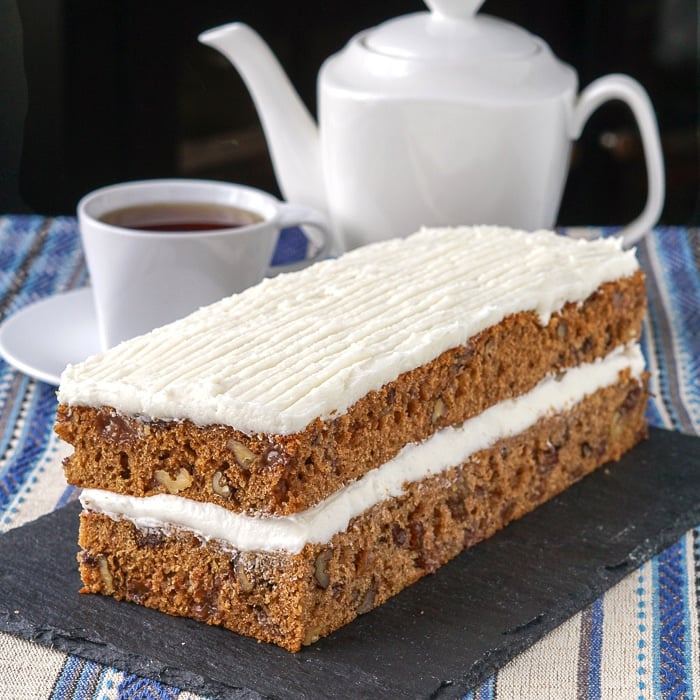 Spanish Bar Cake on a slate serving plate with coffee in the background.