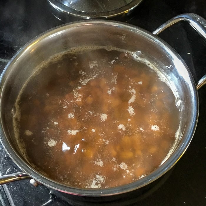 Spanish Bar Cake starts with boiled raisins, shown in saucepan.