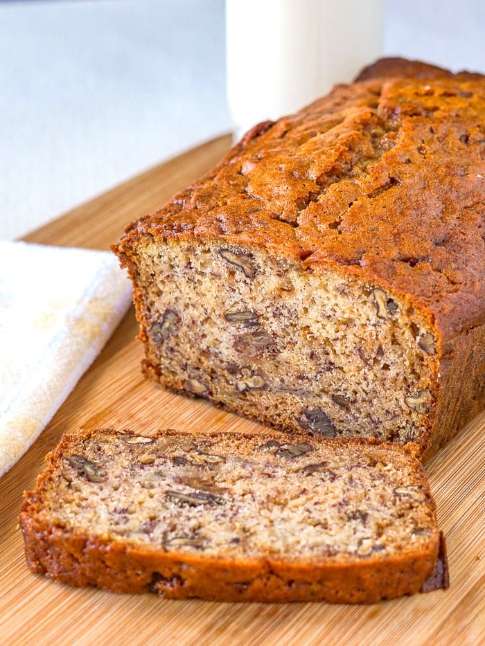 Toffee Pecan Banana Bread vertical photo of cut loaf with glass of milk in background