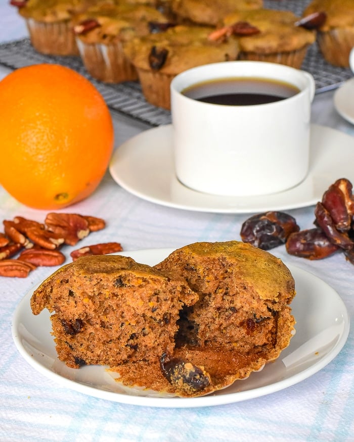 Orange Date Muffins photo of one muffin on a white plate with coffee in the background