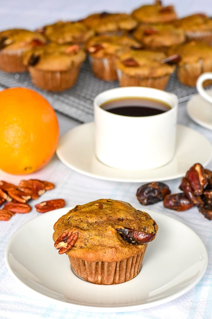 Orange Date Muffins with an orange, dates and pecans in the background