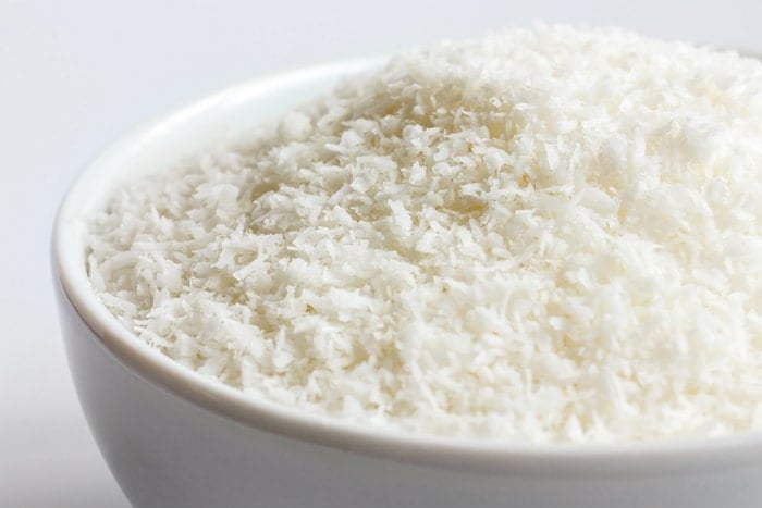 Desiccated coconut in white ceramic bowl.