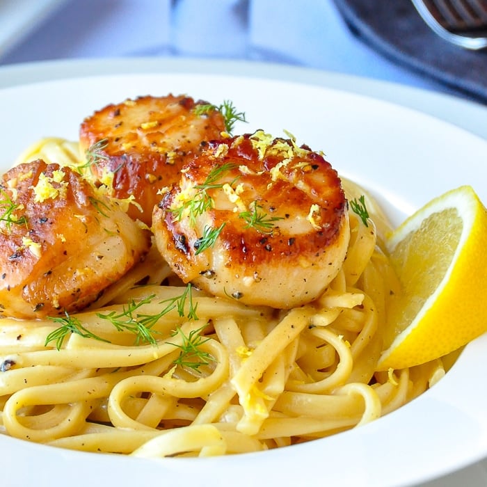 Creamy Lemon Pepper Scallops Linguine close up image in a white bowl.