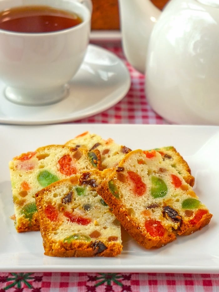 Fruitcake Loaf Cake sliced and served on a white plate with tea