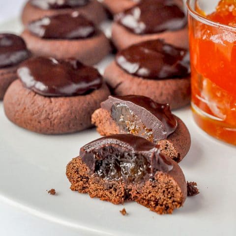 Sachertorte Cookies on a white plate with one cookie cut in half to show filling