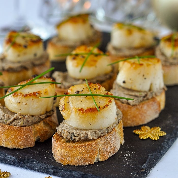 Mushroom Pâté and Seared Scallop Bruschetta shown on a slate serving platter with candles in the background