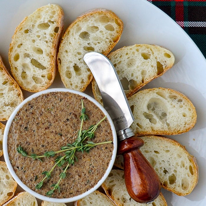 Mushroom Pâté close up featured image with thyme sprigs garnish on a white platter with sliced baguette