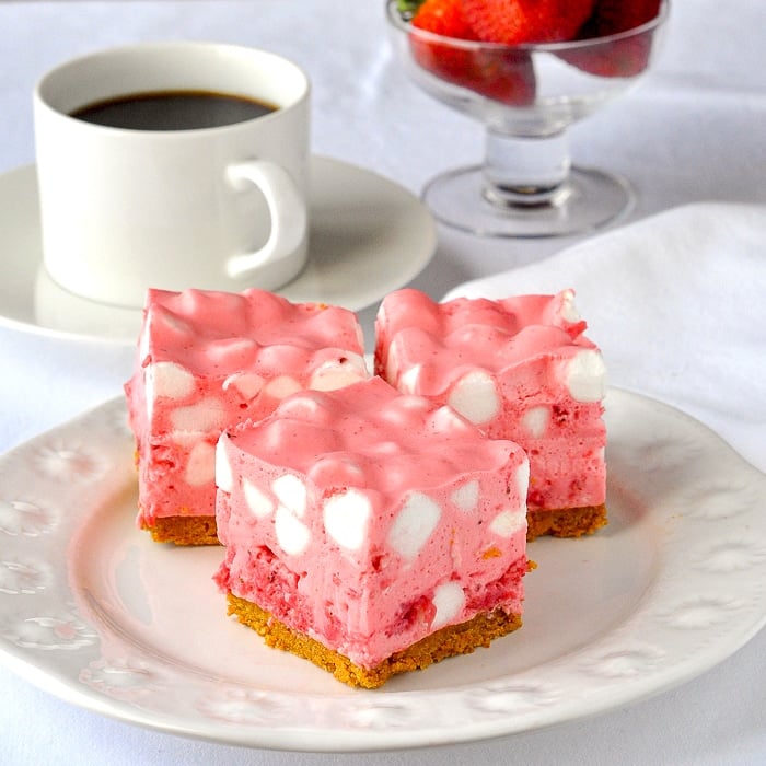 Strawberry Chiffon Squares shown on a white plate with strawberries in the background