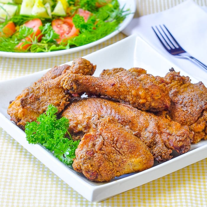 Oven Fried Chicken on a white serving platter with salad in the background.