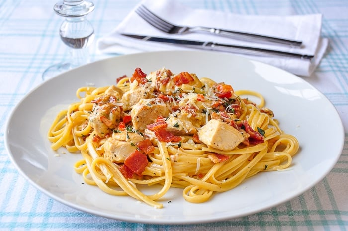 Parmesan Chicken Linguine on a white plate with cutlery and napkin in background