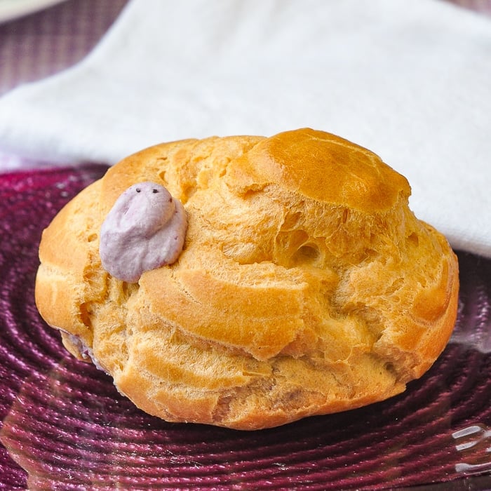 Blueberry Fool Cream Puffs close up photo of one cream puff on a purple glass plate