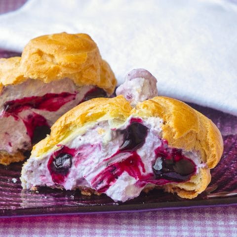 Close up photo of Blueberry Fool Cream Puffs showing one split open to reveal the filling