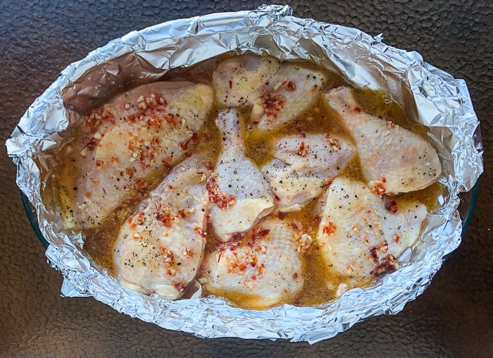 Chicken pieces with sauce poured on ready for the oven