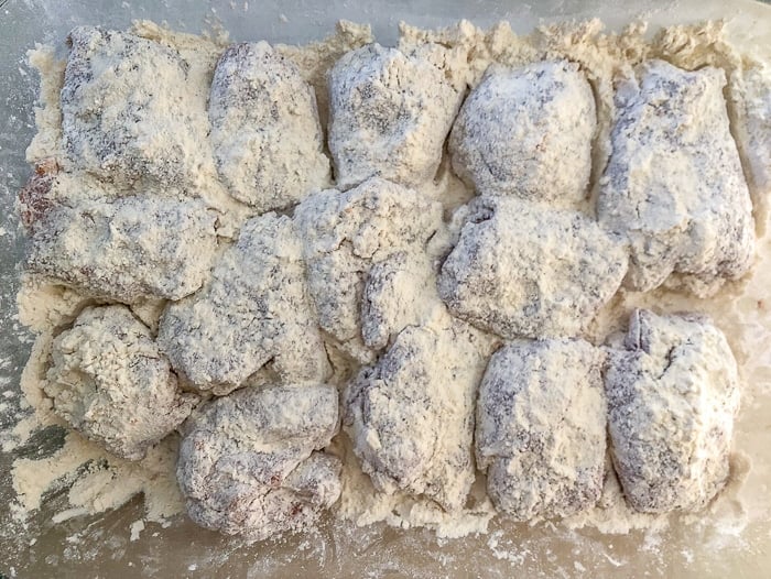 Completely cover the seasoned chicken pieces in flour on both sides