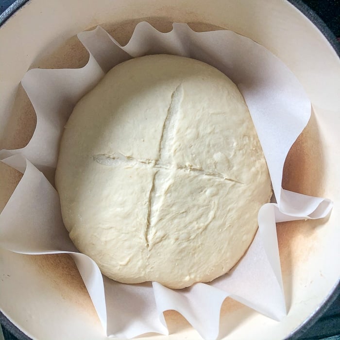 Dough on parchment paper dropped into the hot dutch oven