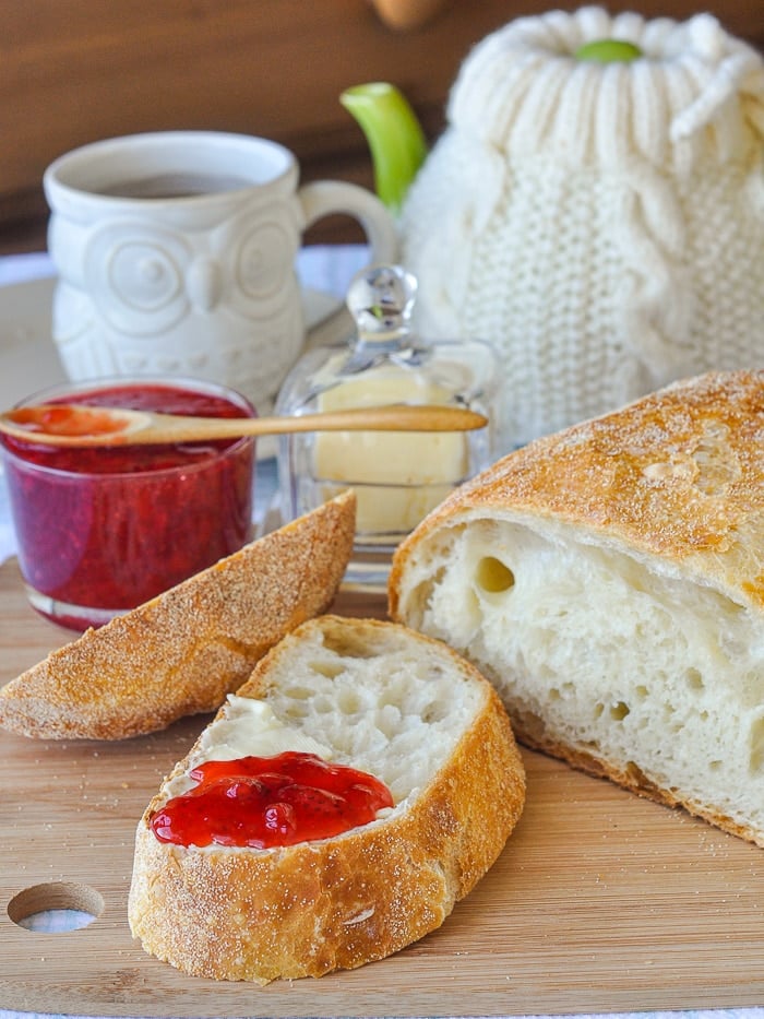 No Knead bread sliced with butter and strawberry jam on it