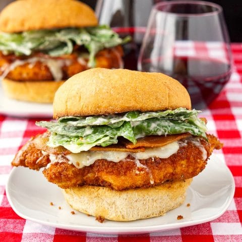 Panko Chicken Caesar Burgers square cropped feature image shown with burgers plus 2 glasses of wine in the background