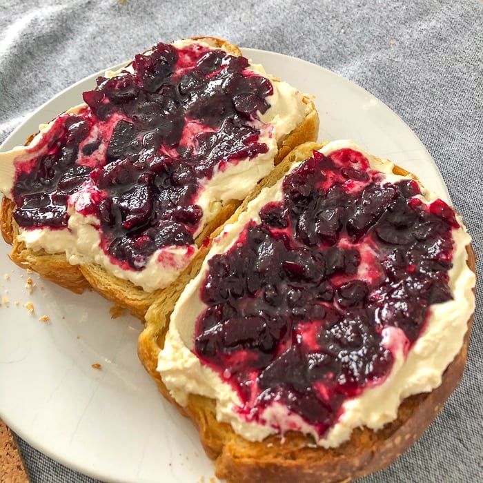 White bread with jam and cream on a white plate.