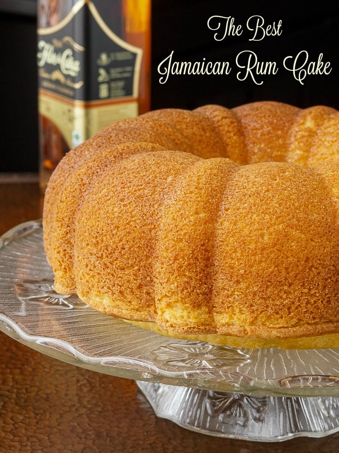 Jamaican Rum Cake on a glass pedestal stand with title text added for Pinterest