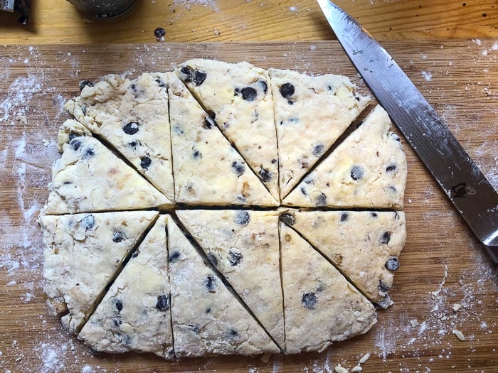 Scone dough cut into triangles on a wooden cutting board.