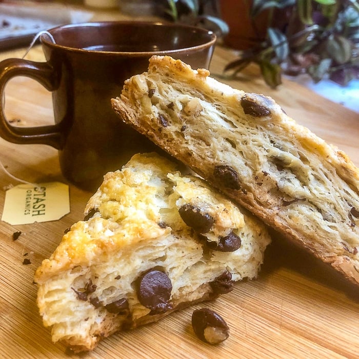 Chocolate Chip Walnut Scones on a wooden board with a cup of tea.