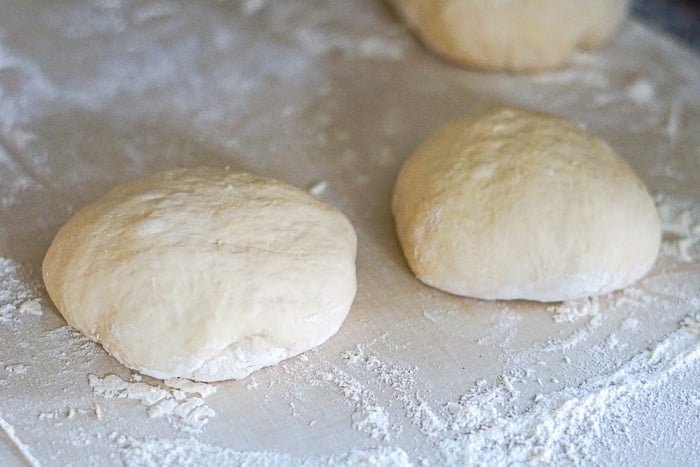 No knead pizza dough in 3 balls on a floured countertop