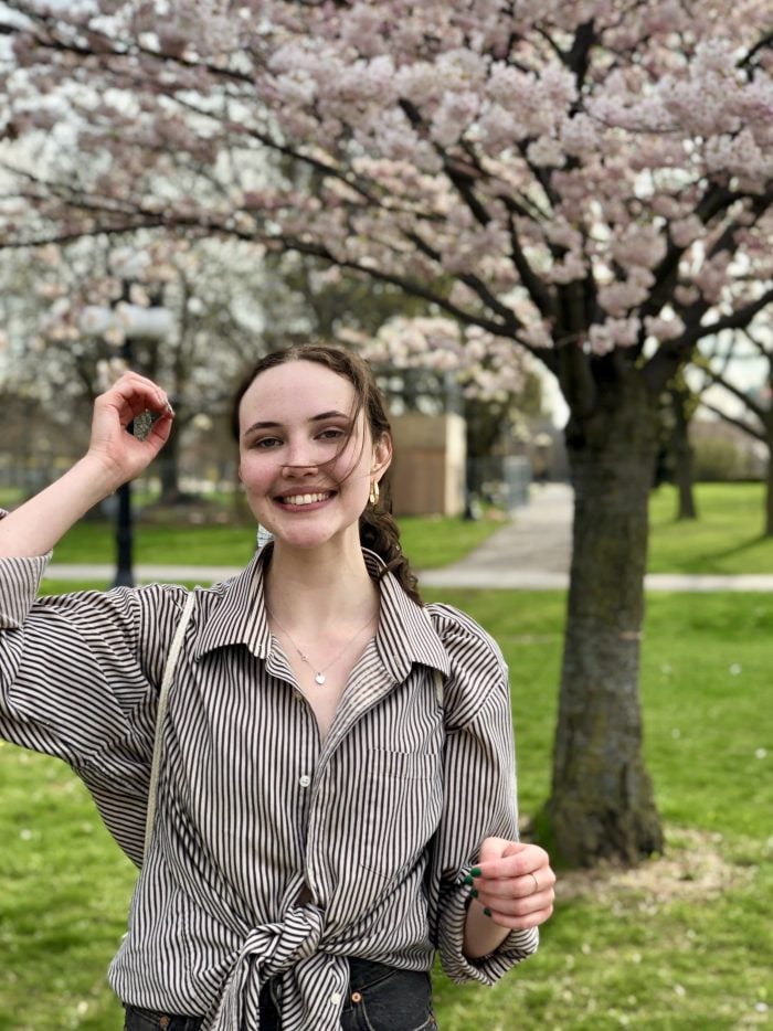 Photo of Olivia with blooming cherry tree in the background.