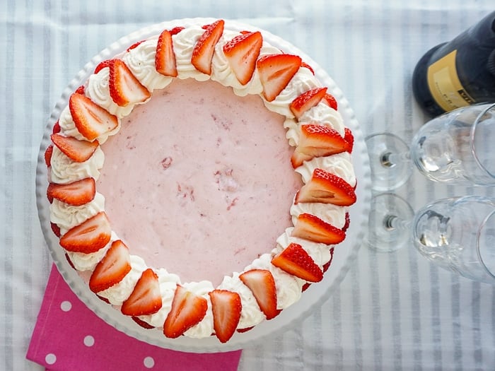 Strawberry Marshmallow Mousse Cake wide shot photo of entire finished cake on a white pedestal