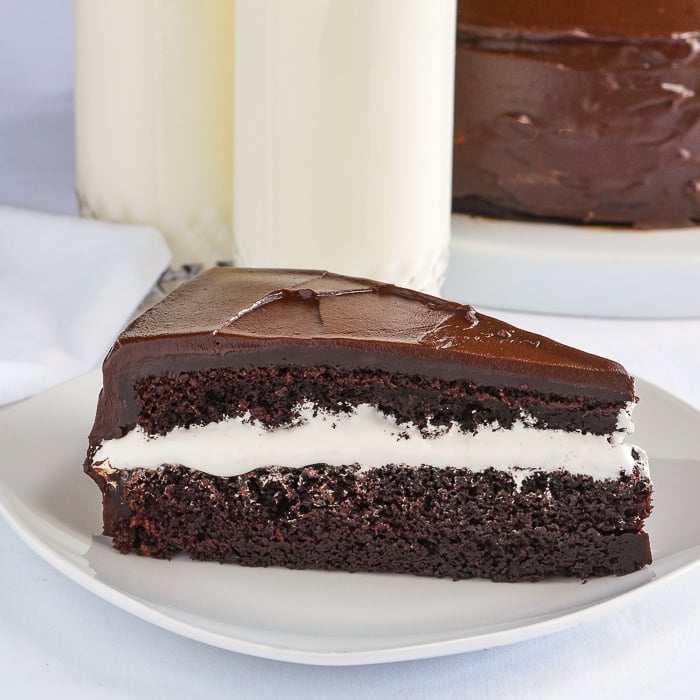 Jos Louis Cake photo of a slice on a white plate with glasses of milk in the background