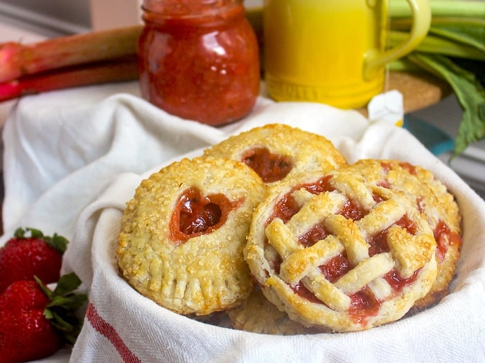 Oven baked hand pies pictures with jam, strawberries and rhubarb in the background