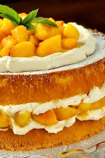 Bourbon Peach Shortcake close up photo of uncut cake with fresh peaches on the side