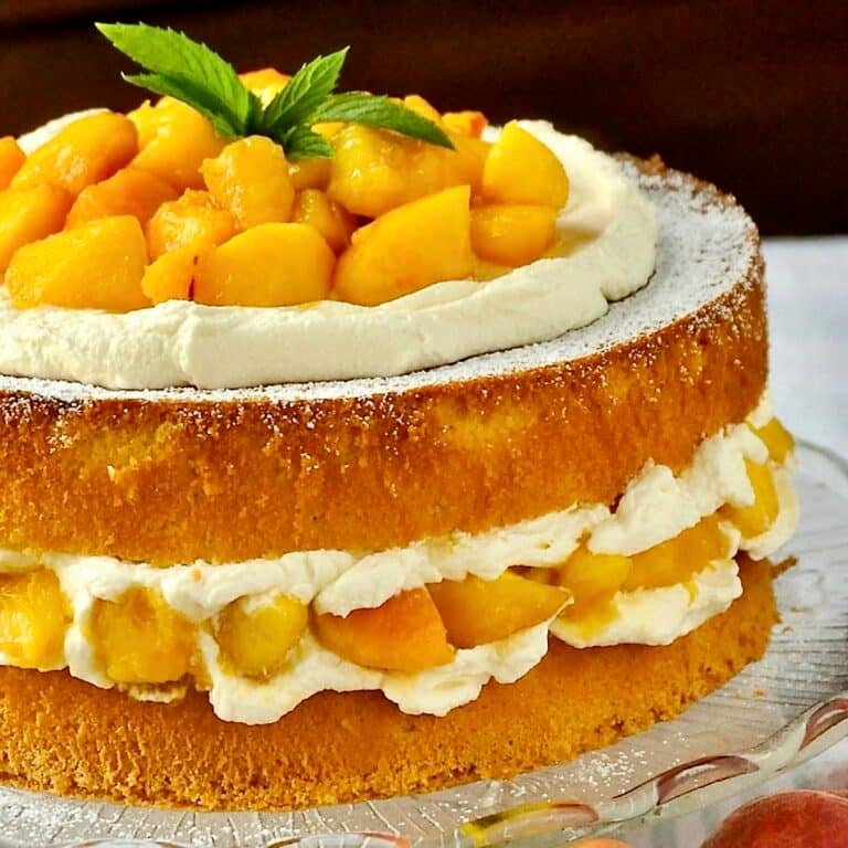 Bourbon Peach Shortcake close up photo of uncut cake with fresh peaches on the side