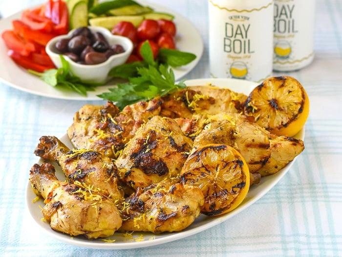Grilled Lemon Chicken photo of chicken on a whiote platter with salad in background