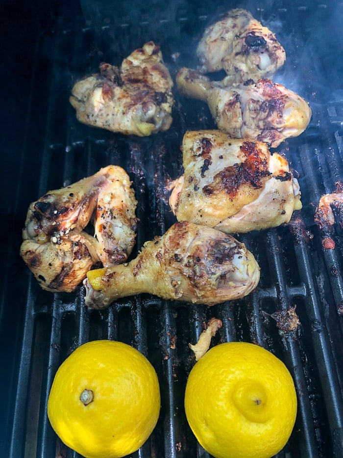 Grilled lemon chicken and lemon halves on a hot grill