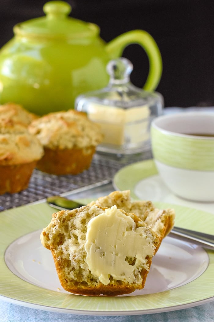 Multigrain Muffins photo of a muffin with butter dpread on hald with tea service in the background