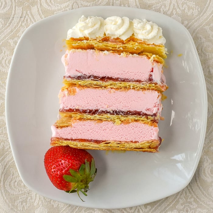 Strawberry Mille Feuille Ice Cream Cake photo of a single slice with a strawberry garnish on a white plate