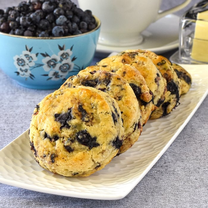 Blueberry Tea Buns on a whote rectangular serving pate with berries and butter in the background