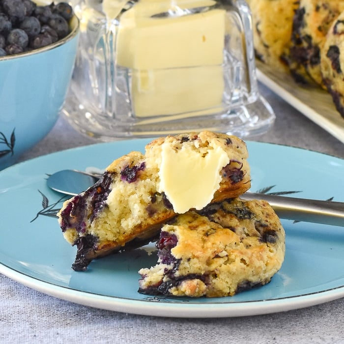 Blueberry Tea Buns photo of a single bun with butter on a blue floral plate