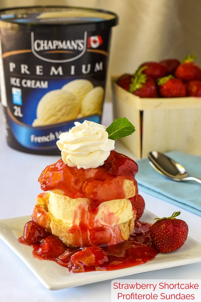 Strawberry Shortcake Profiterole Sundaes with strawberries and Chapman's French Vanilla ice cream in the background and title text added at bottom for Pinterest