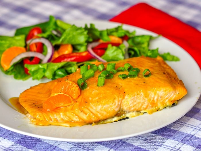 Ginger Orange Glazed Salmon shown with a mixed salad on a white plate.