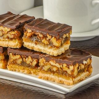 Chocolate Pecan Bars closeup square cropped photo of cookie bars on a white plate-1