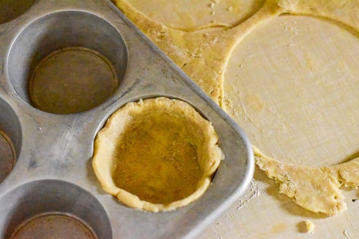Fit pastry circles into a muffin pan.