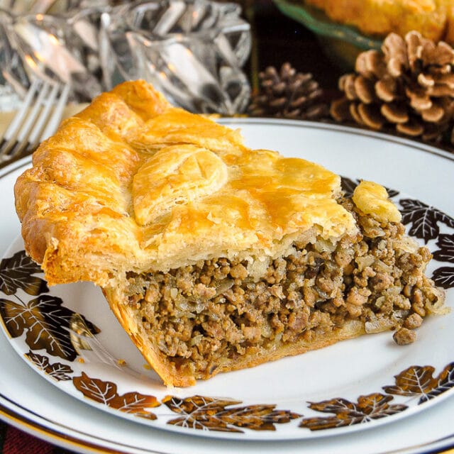A slice of Christmas Tourtière on a white and gold plate