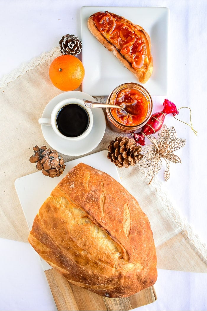 Overhead photo of marmalade, bread and christmas decorations all on a white tablecloth