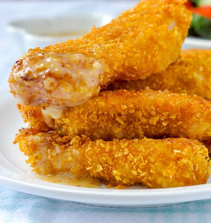 Crispy Cornflake Fish Sticks photo of fish sticks dipped in honey dijon sauce.