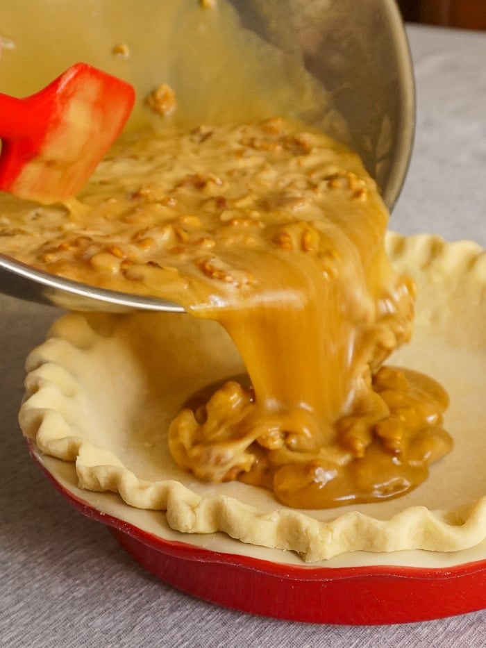 Pouring the filling for Maple Walnut Pie into an unbaked pastry shell